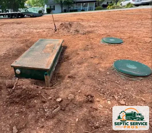 Newly installed septic tank with green riser lids set at grade on a cleared lot