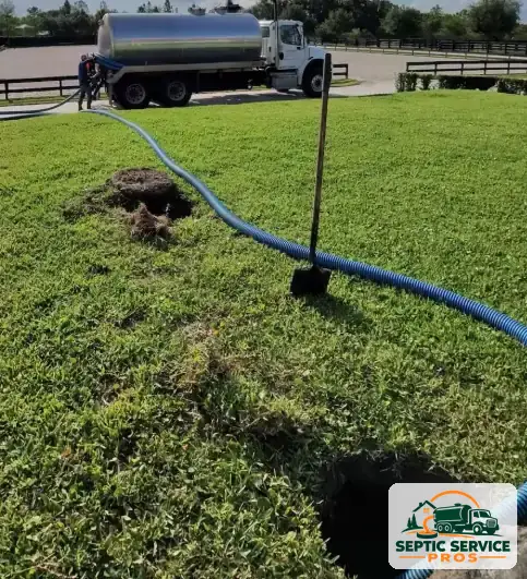 Pump truck on a horse property with a long hose run across the lawn to an opened septic tank